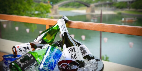 Variedad de botellas de vidrio verde y transparente con etiquetas, sobre hielo, con una barandilla de madera y un cuerpo de agua al fondo.