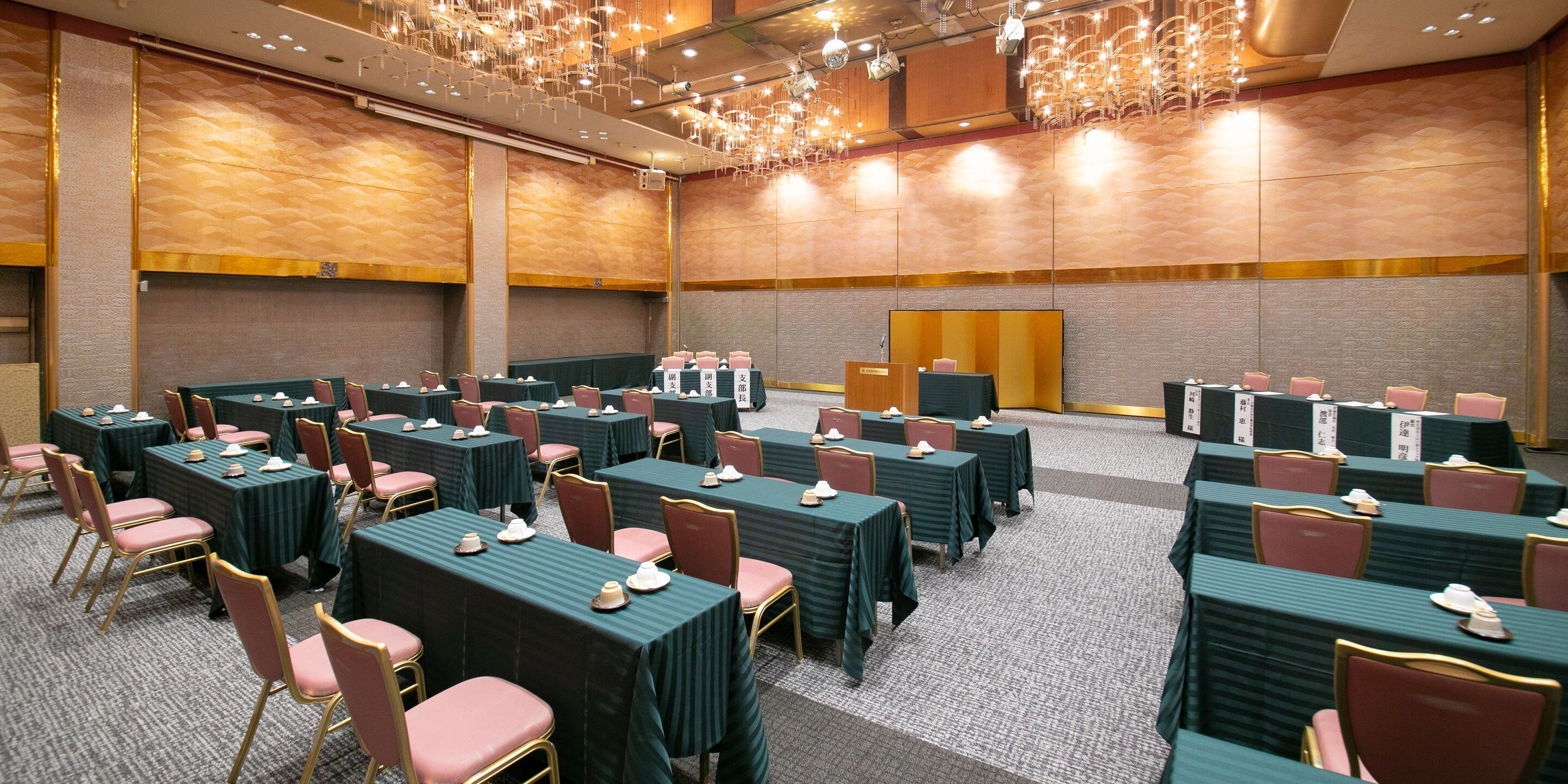 A conference room with rows of tables and chairs, equipped with nameplates and table settings.