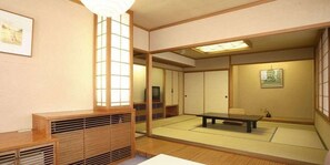 A traditional Japanese room with tatami flooring, a low table, sliding doors, and a television. - Kaike Onsen Tokoen (Yonago)