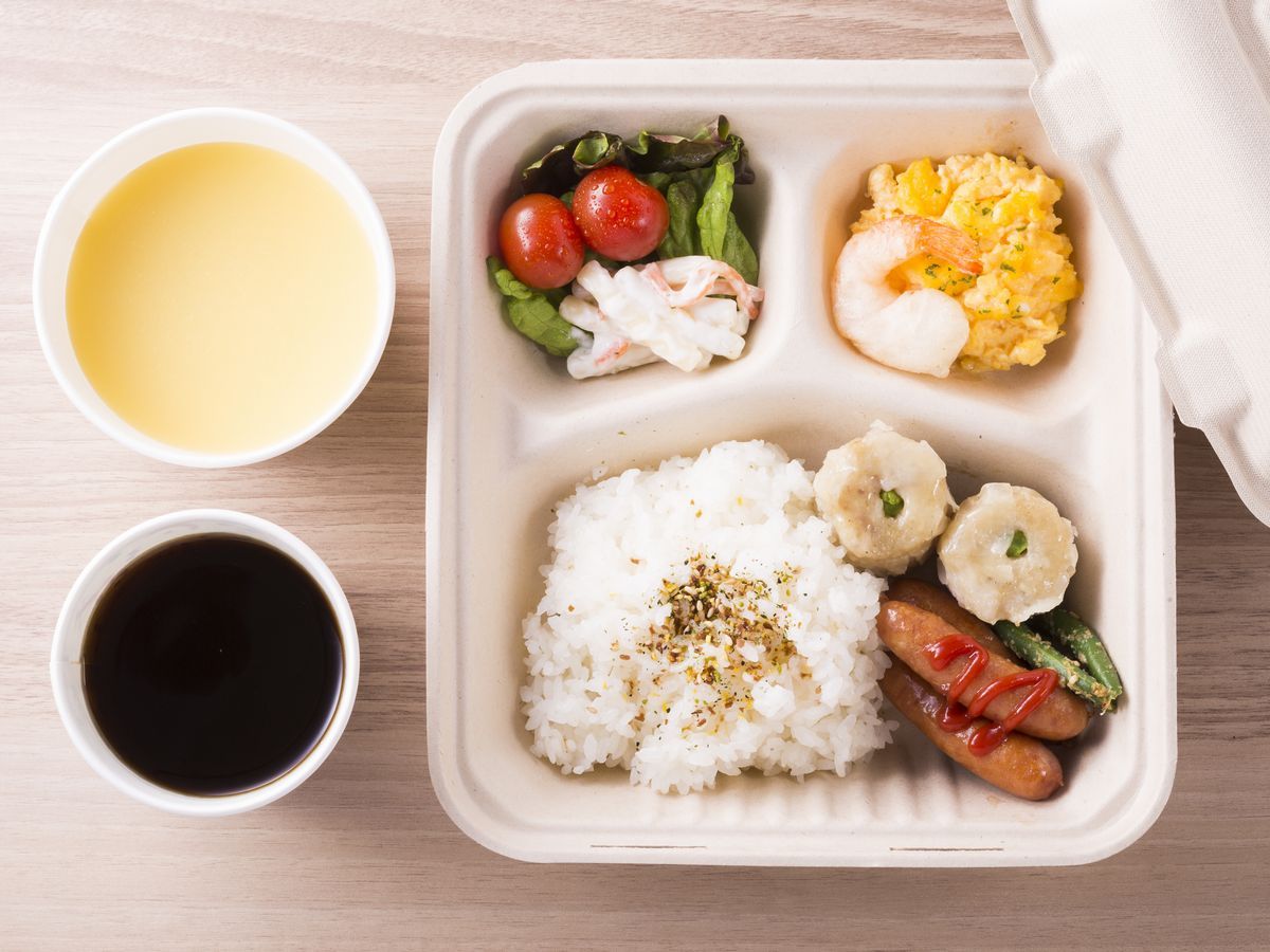 A meal in a takeout container with rice, shrimp, and vegetables.