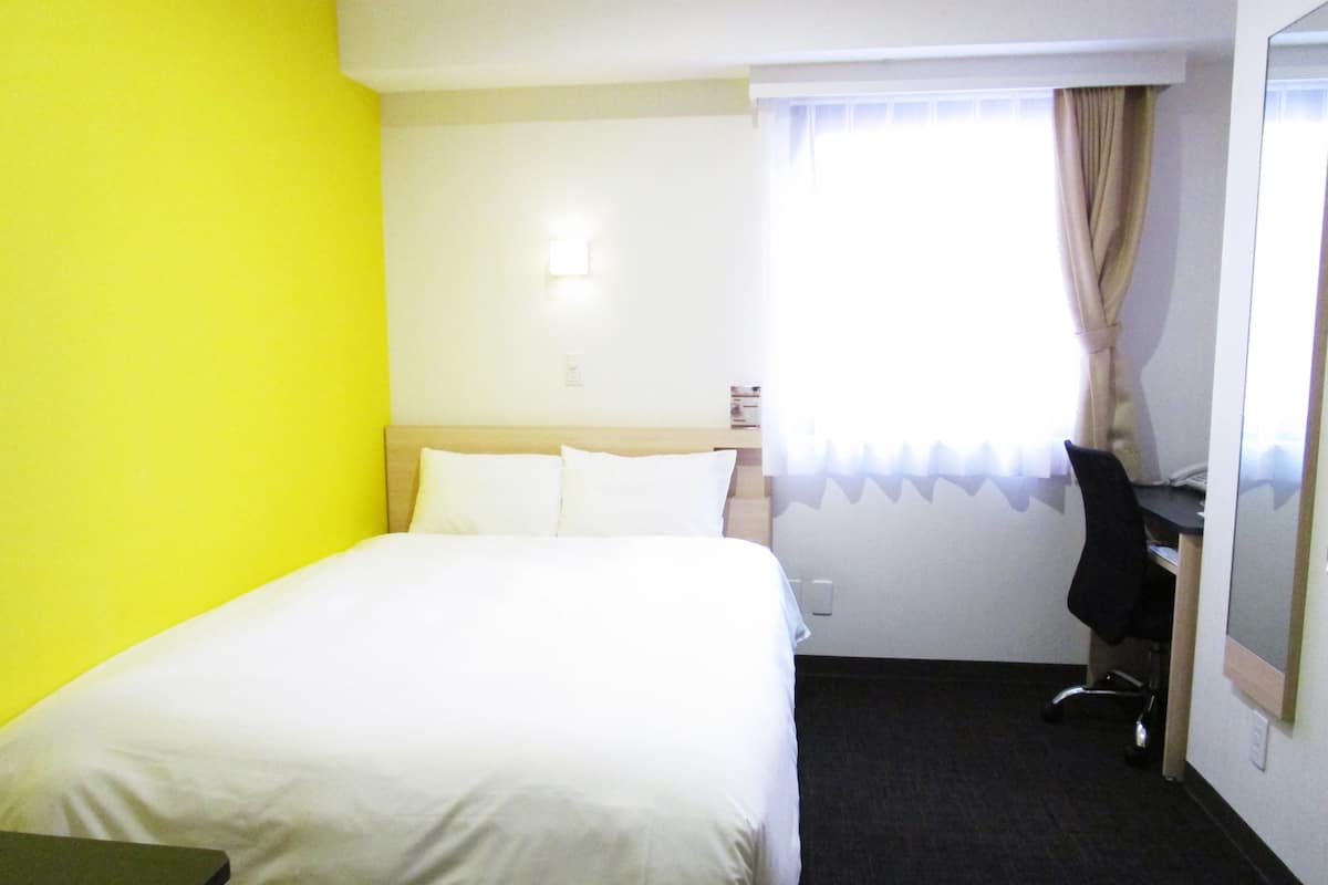 Quarto de hotel com uma cama, uma mesa e uma cadeira.