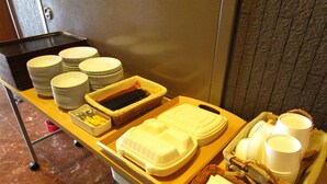 A buffet setup with stacked plates, bowls, and containers on a wooden table. - Smile Hotel - Utsunomiya Higashiguchi (Utsunomiya)