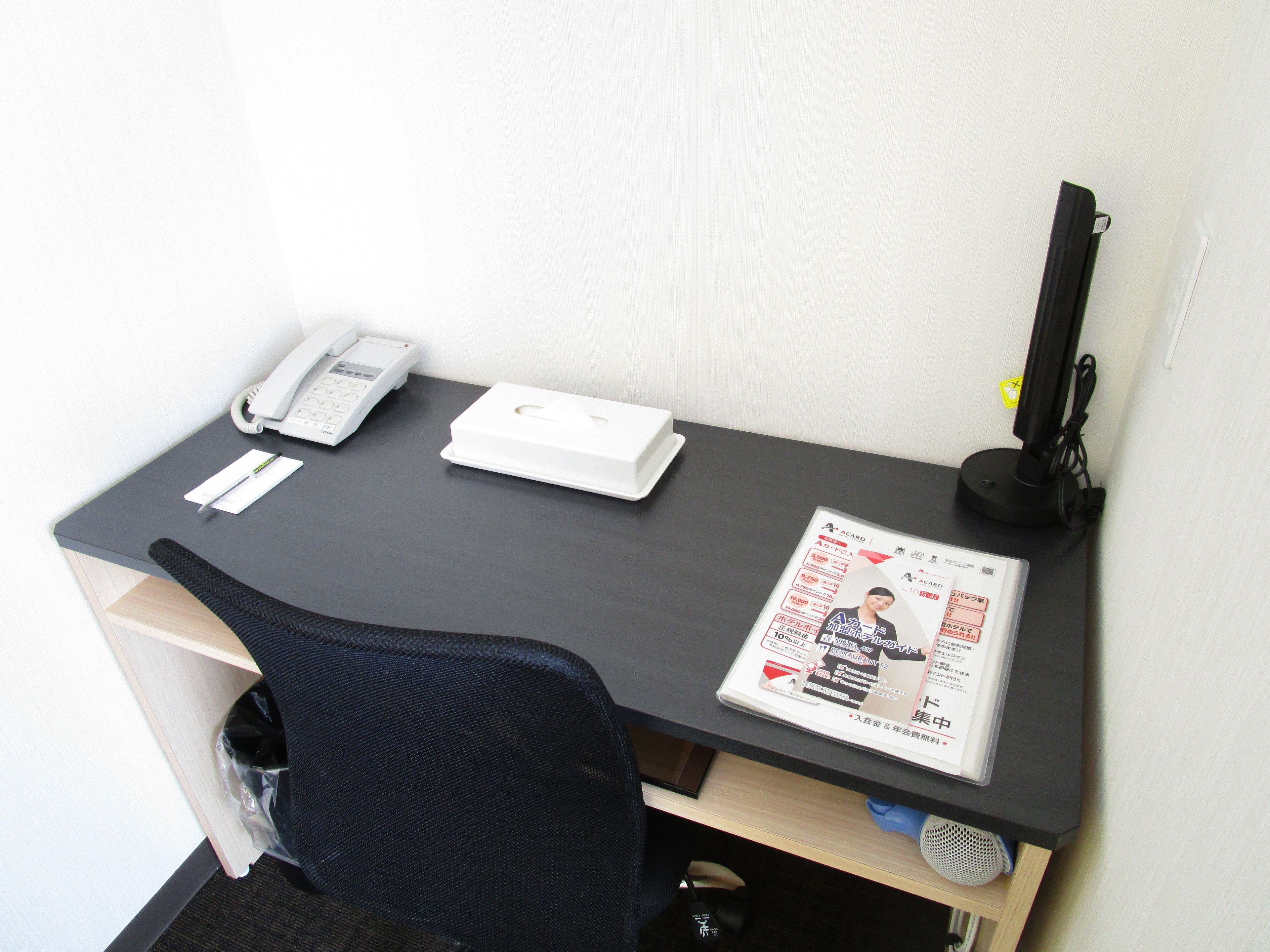 A desk with a telephone, a white box, and a magazine.