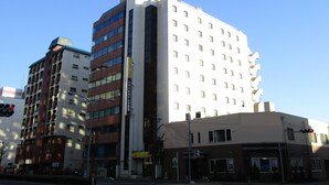 A multi-story hotel with a prominent yellow sign at the top, a large glass facade, and a modern architectural design. - Smile Hotel - Utsunomiya Higashiguchi (Utsunomiya)
