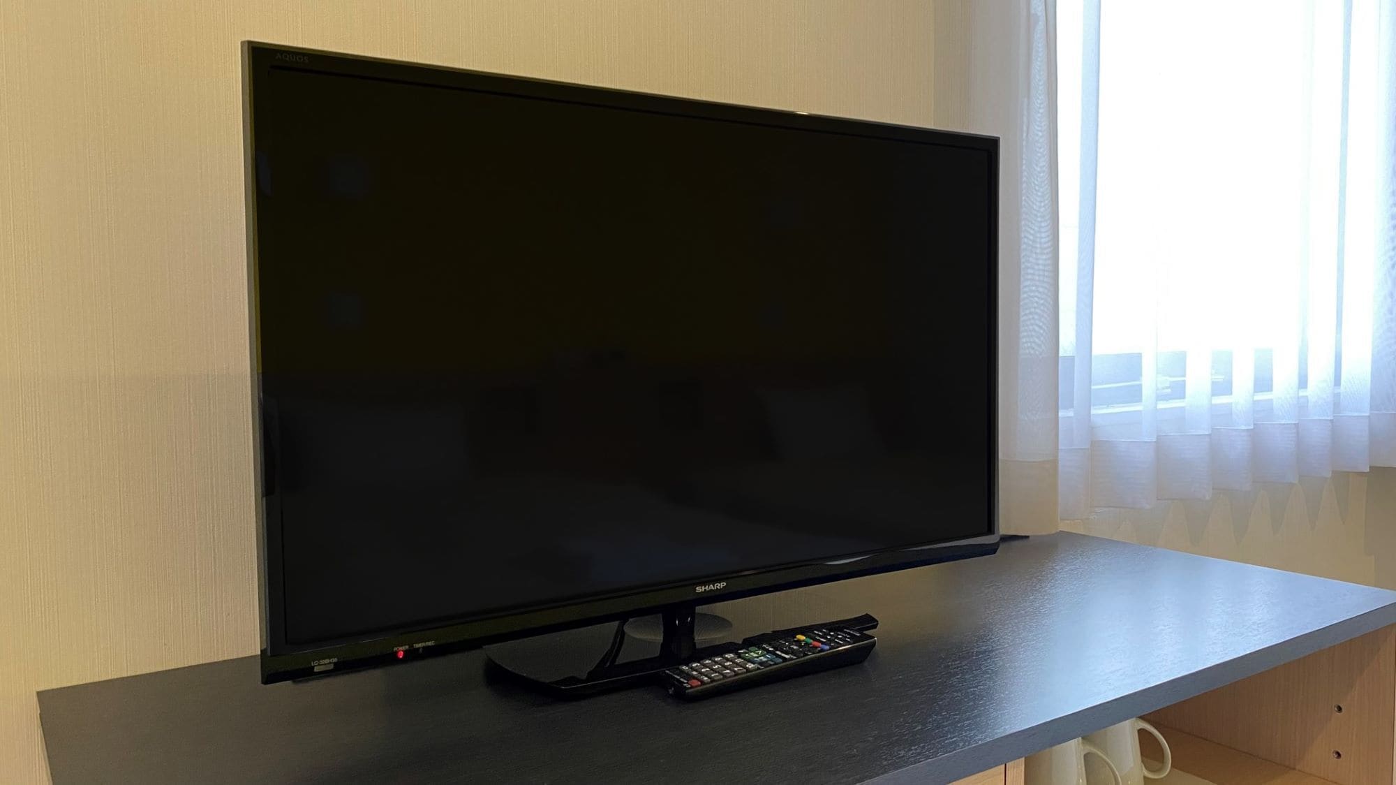 A flat-screen TV on a dark wooden stand with a remote control.