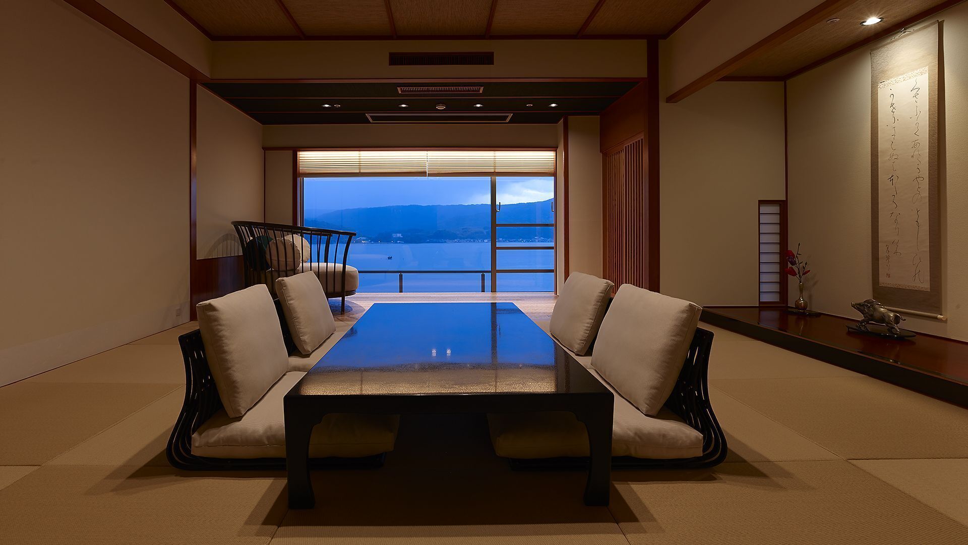 A conference room with a large table, two chairs, a view of the sea, and traditional decor.