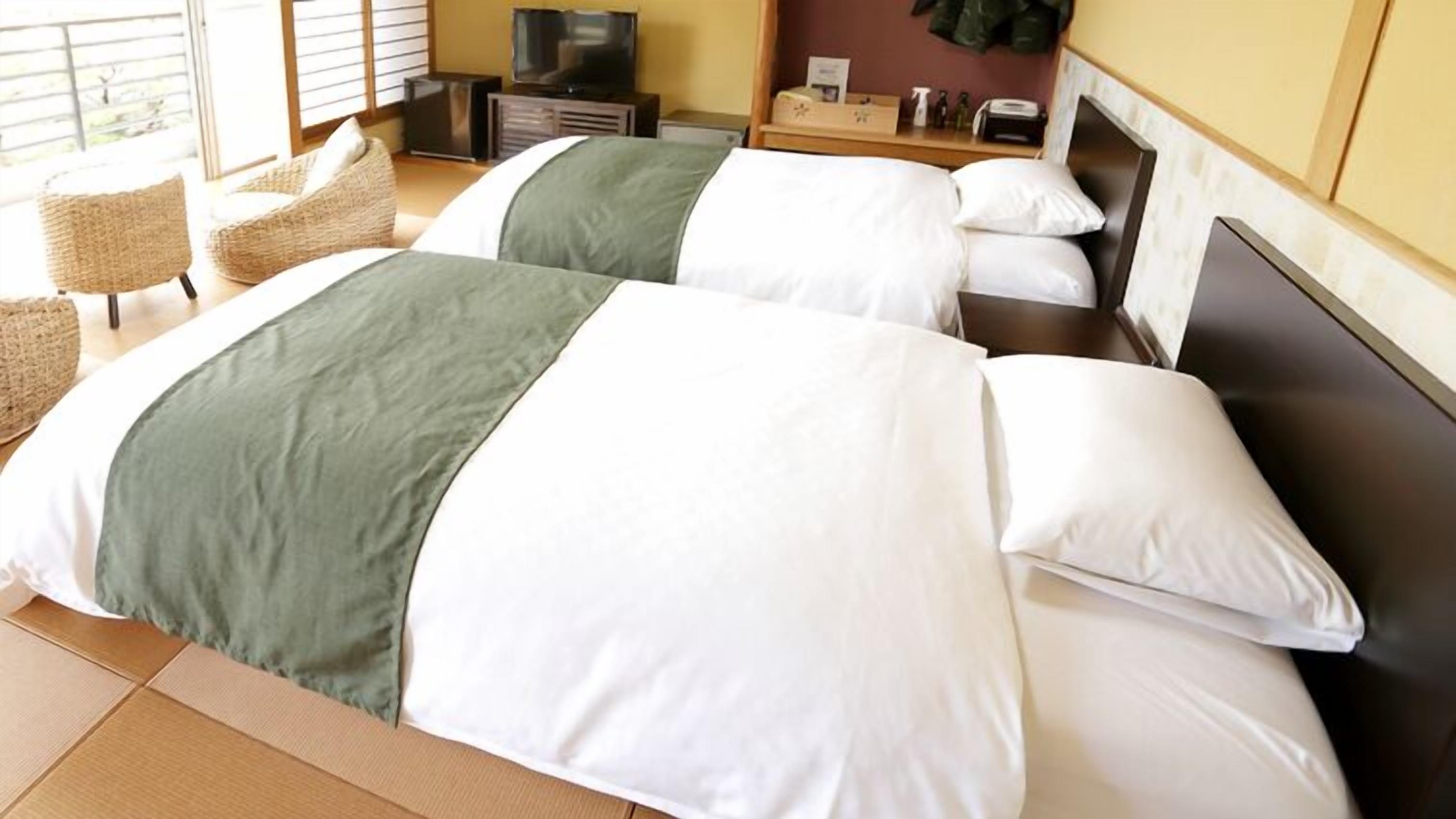 A hotel room with two beds, a television, a small table, and a chair.