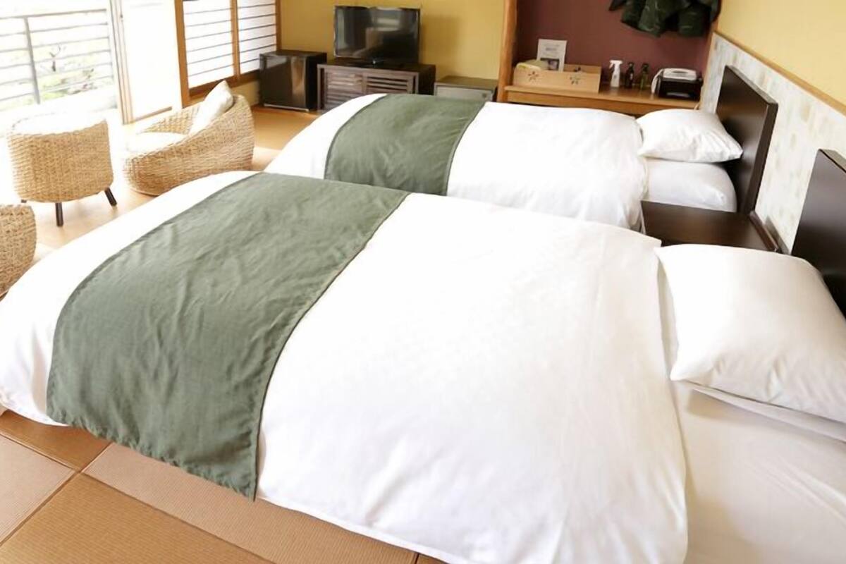 Habitación de hotel con dos camas, un televisor, una mesita y una silla.