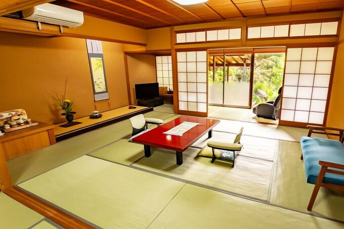 Una habitación con tatami, una mesa baja, un sofá y un televisor.