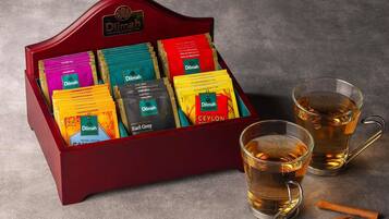 Une présentation de différents types de thé en sachets, accompagnée de deux verres de thé.