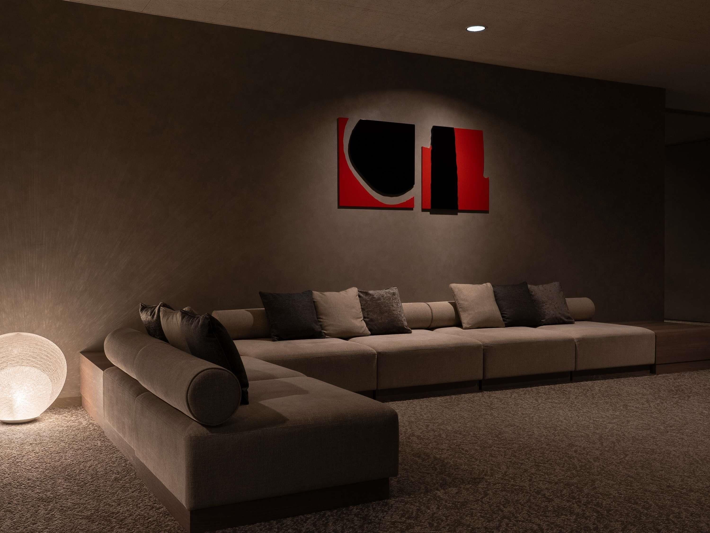 Una sala moderna con un sofá modular, una lámpara de pie y arte abstracto en la pared.