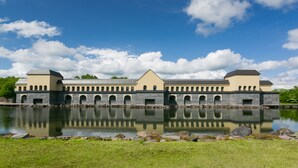 En stor bygning med et centralt tårn, spændende buede vinduer og et spejlbillede i vandet.