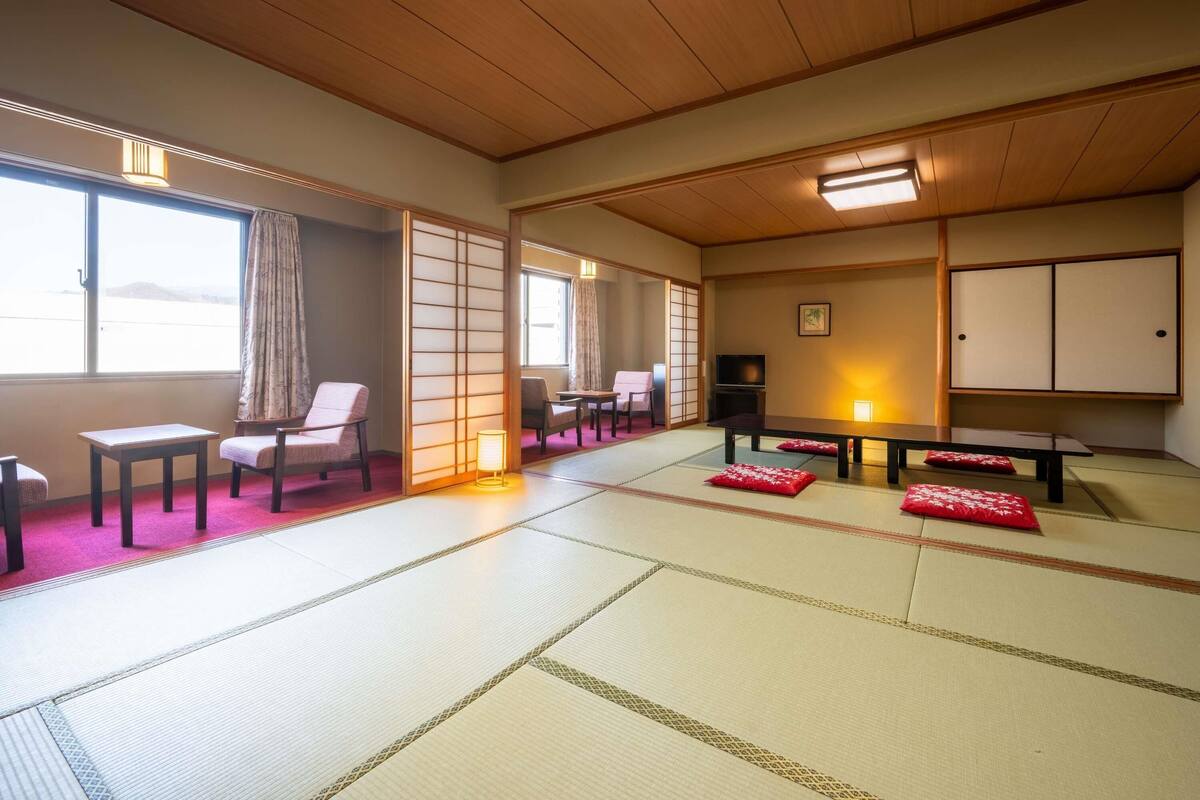 A traditional Japanese room with tatami flooring, sliding doors, and a low table with cushions.