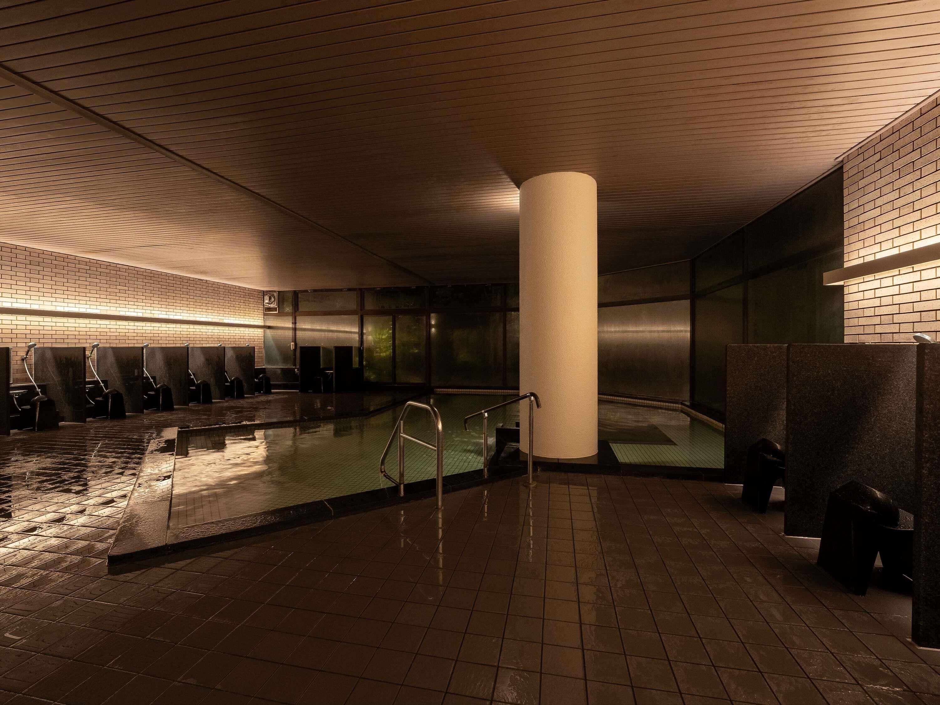 A public indoor swimming pool with multiple lanes, a central column, and a tiled floor.