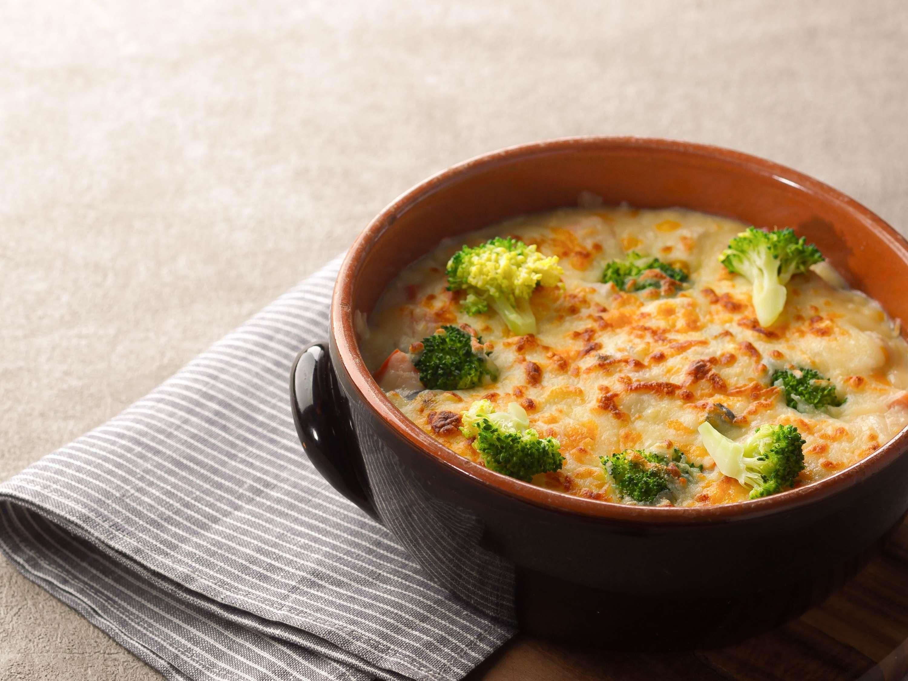 Un tazón de sopa con brócoli y queso sobre una mesa.