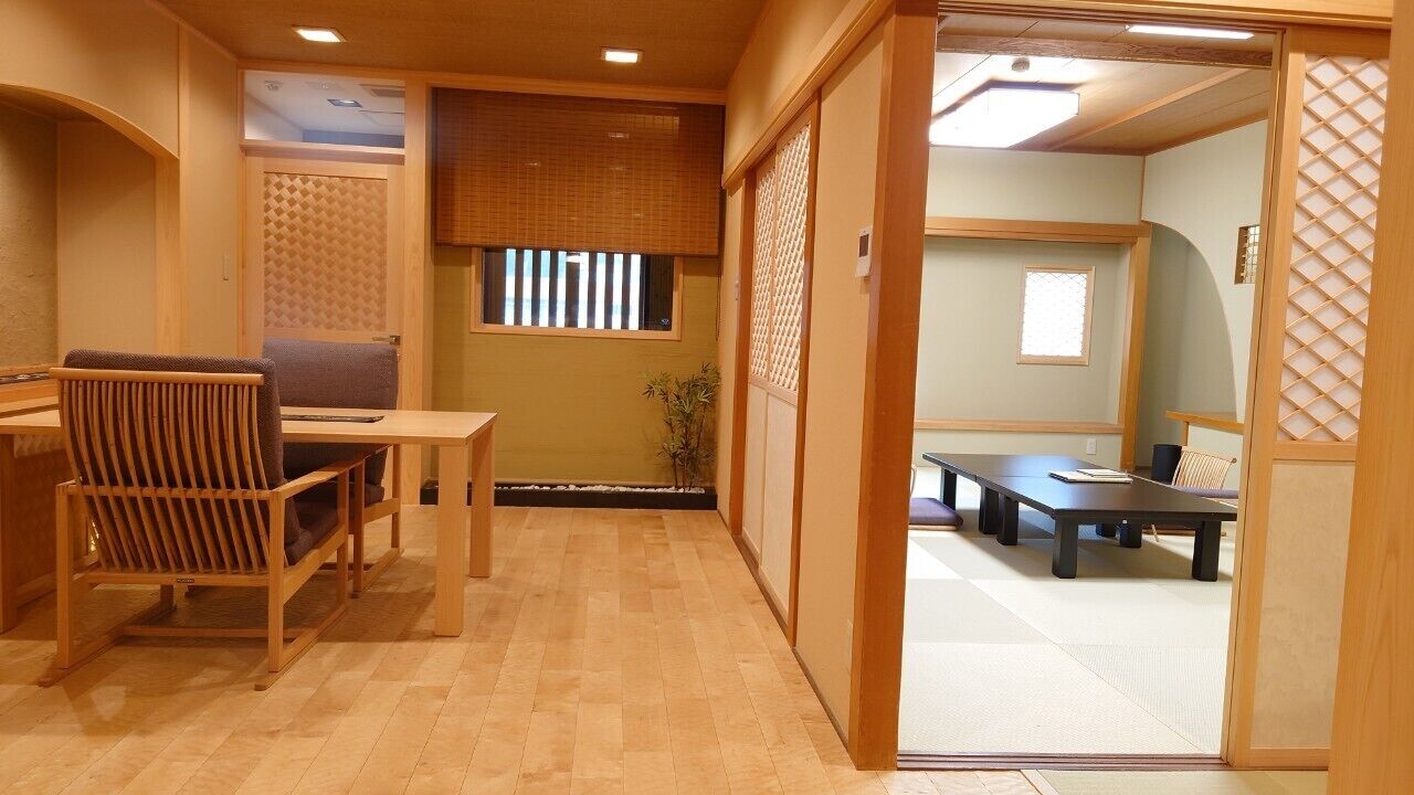 A traditional Japanese room with tatami flooring, a low table with a cushion, and sliding doors.