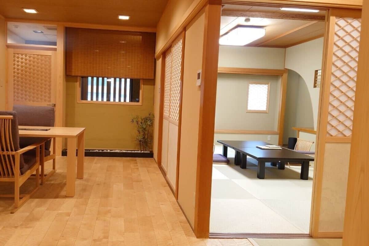 A traditional Japanese room with tatami flooring, a low table with a cushion, and sliding doors.
