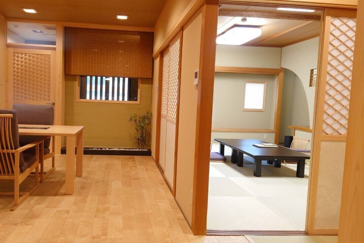 A traditional Japanese room with tatami flooring, a low table with a cushion, and sliding doors.