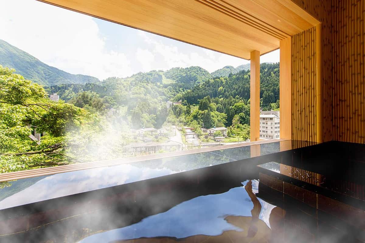 A spa area with a hot tub, wooden ceiling, and a view of a mountainous landscape.