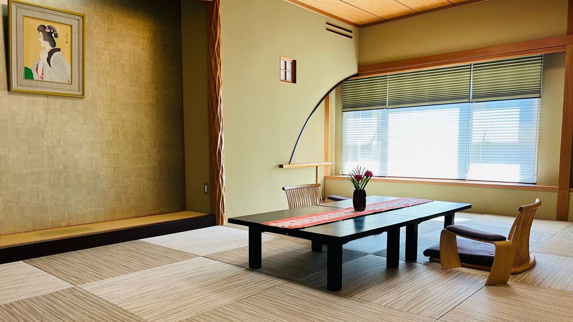 Una habitación japonesa tradicional con suelo de tatami, una mesa baja, una silla y una ventana con persianas.