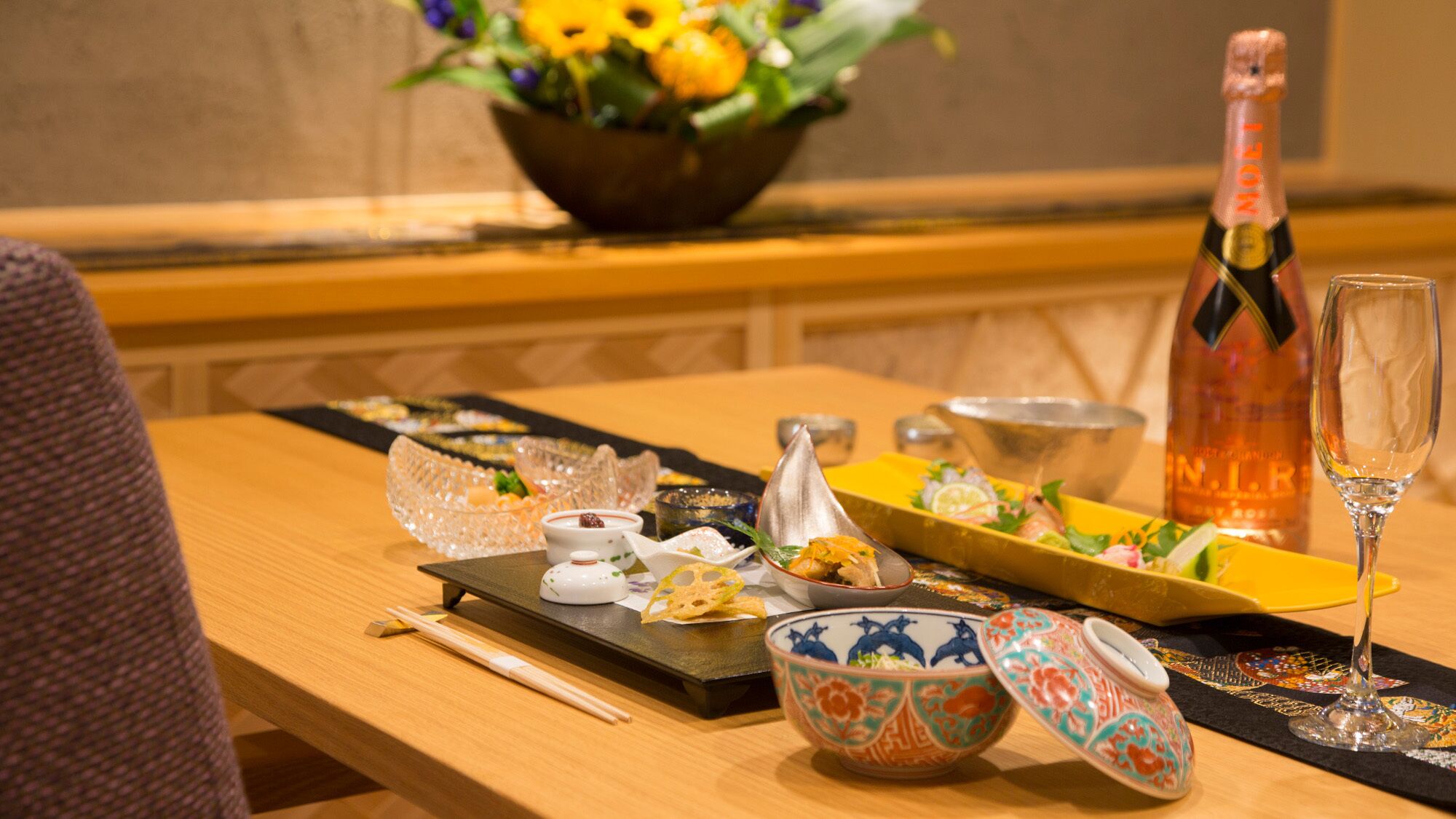 A table set with various dishes, a bottle of champagne, and a glass.