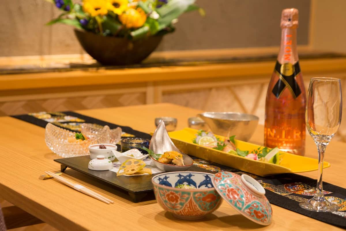 A table set with various dishes, a bottle of champagne, and a glass.