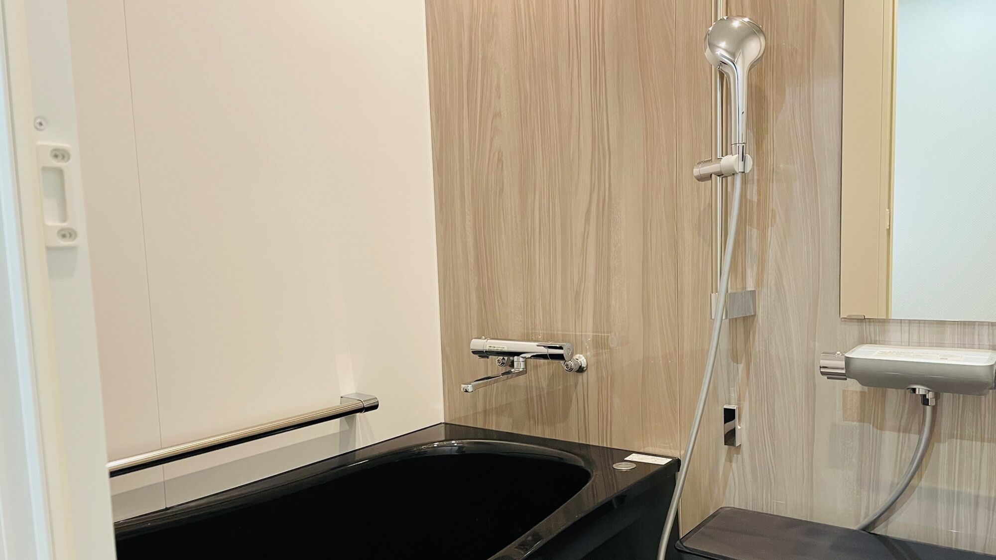 A modern bathroom with a black bathtub, a wooden vanity, and a shower with a handheld showerhead.