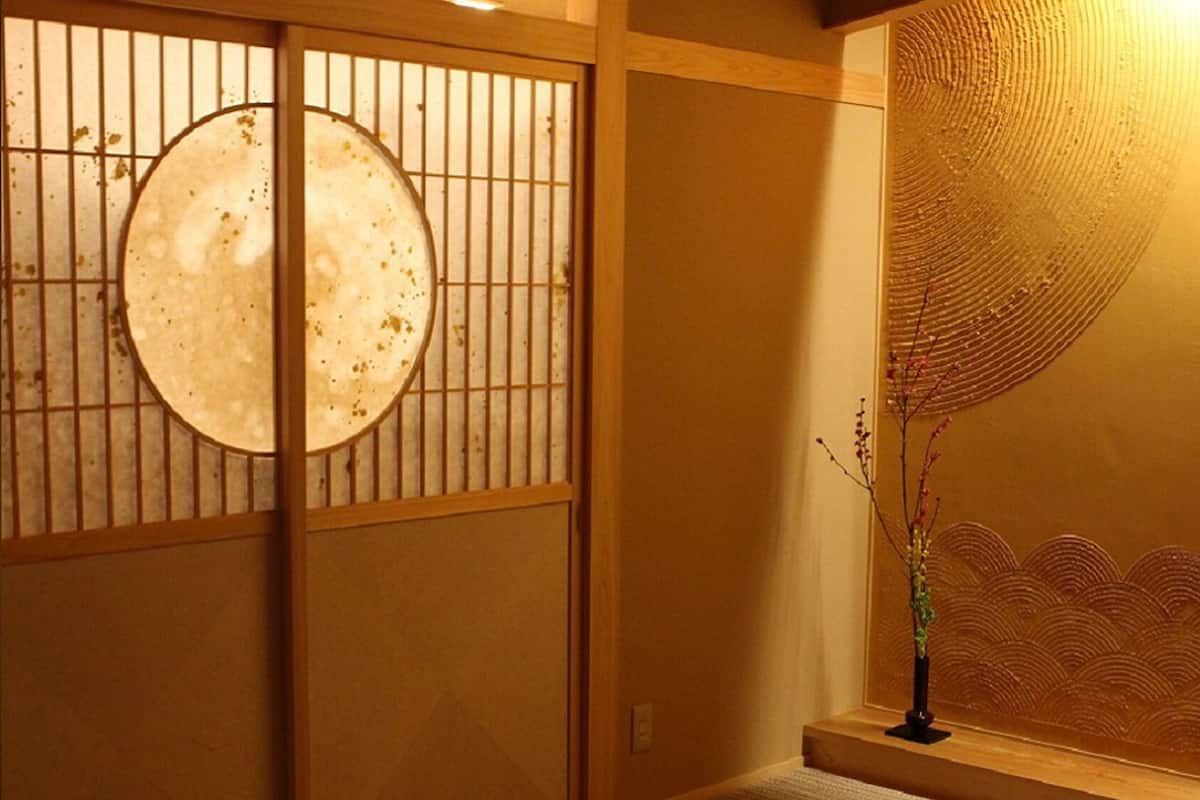 A traditional Japanese room with sliding doors, a decorative wall, and a small table with a vase.