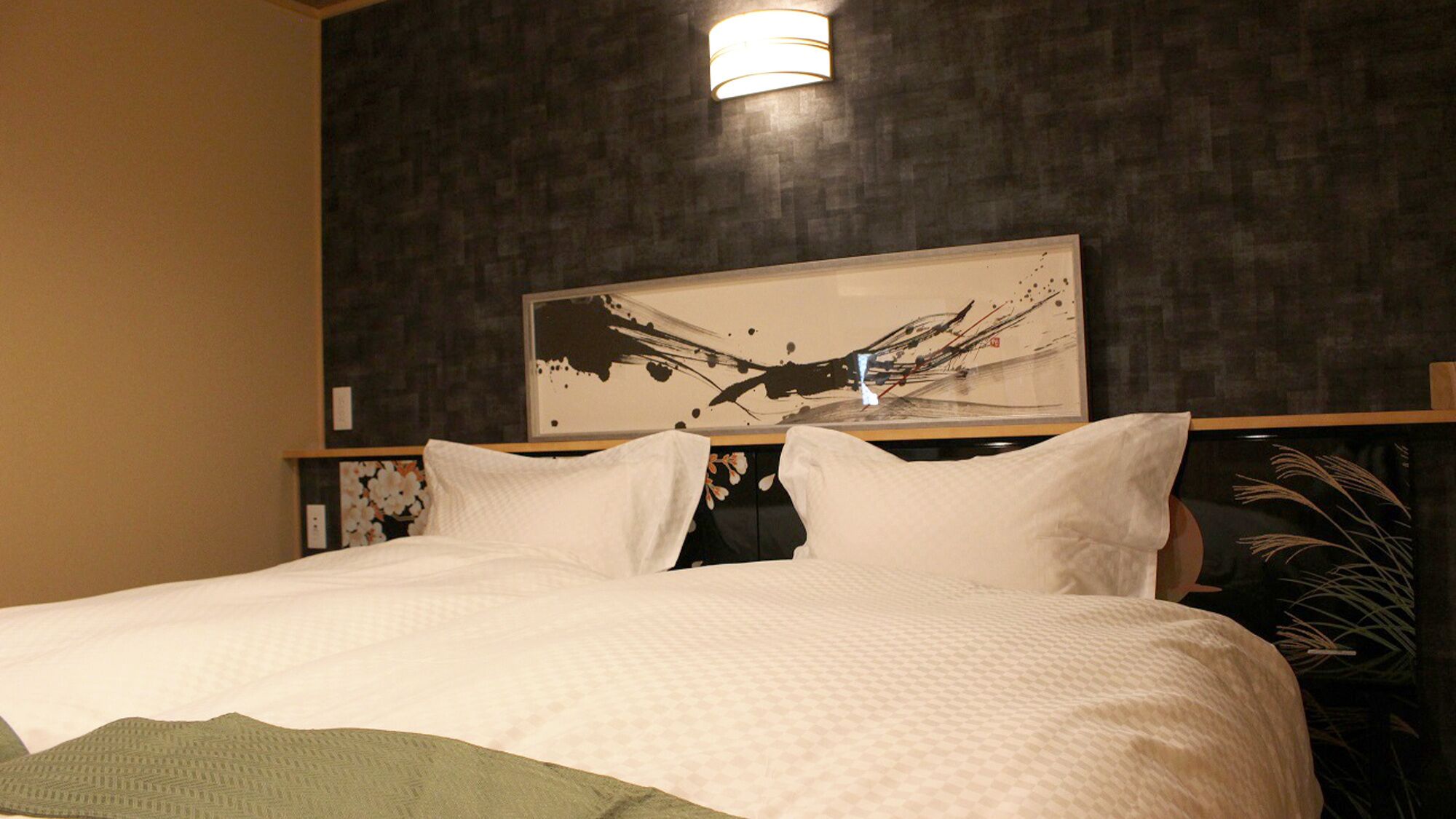 A hotel room with a large bed, a dark textured wall, and a modern abstract painting above the bed.