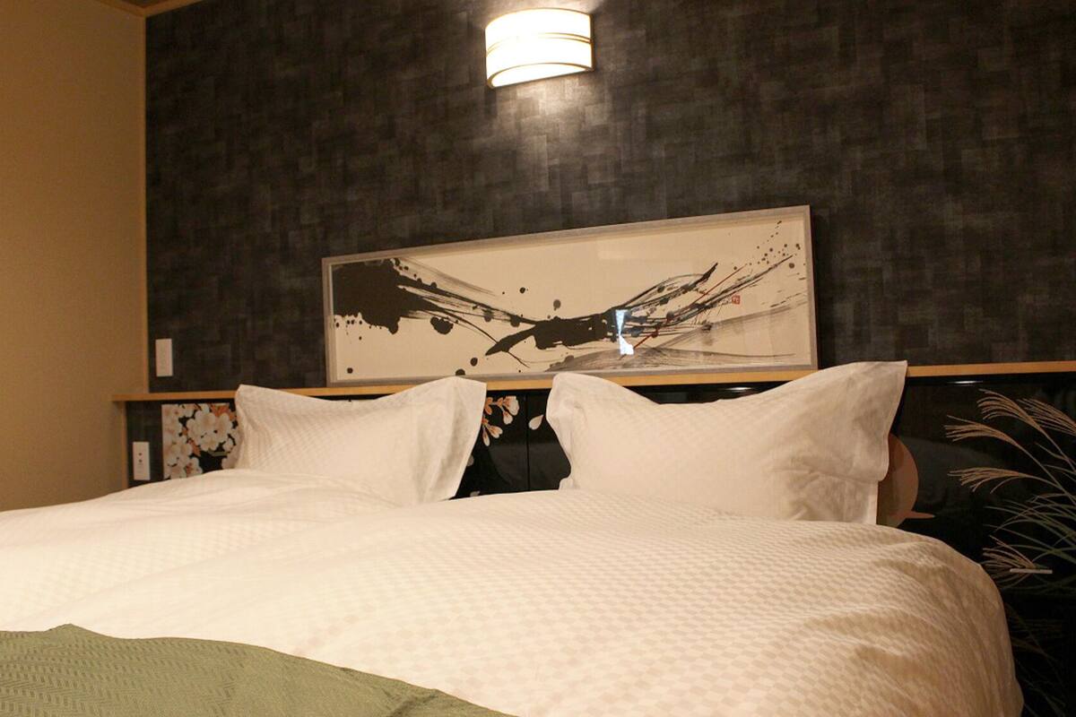 A hotel room with a large bed, a dark textured wall, and a modern abstract painting above the bed.