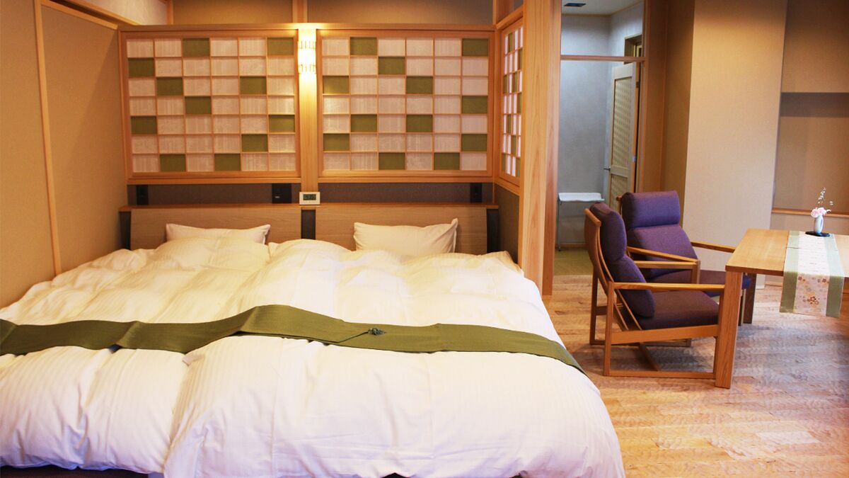 Una habitación de hotel con una cama grande, un cabecero de madera, una silla y una mesita.