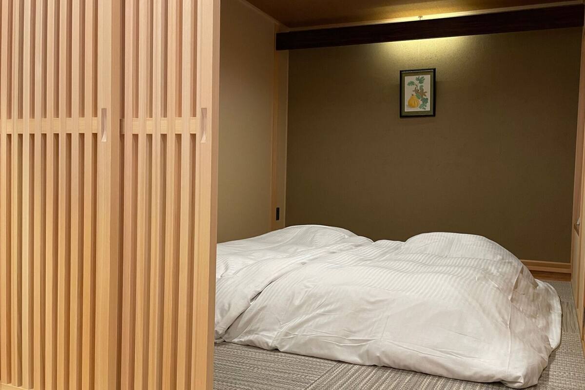 A room with a bed, a wooden slat partition, and a framed picture on the wall.