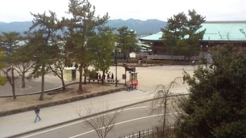 Un espacio pavimentado con bancos y un pequeño quiosco, rodeado de árboles y un edificio con techo verde.