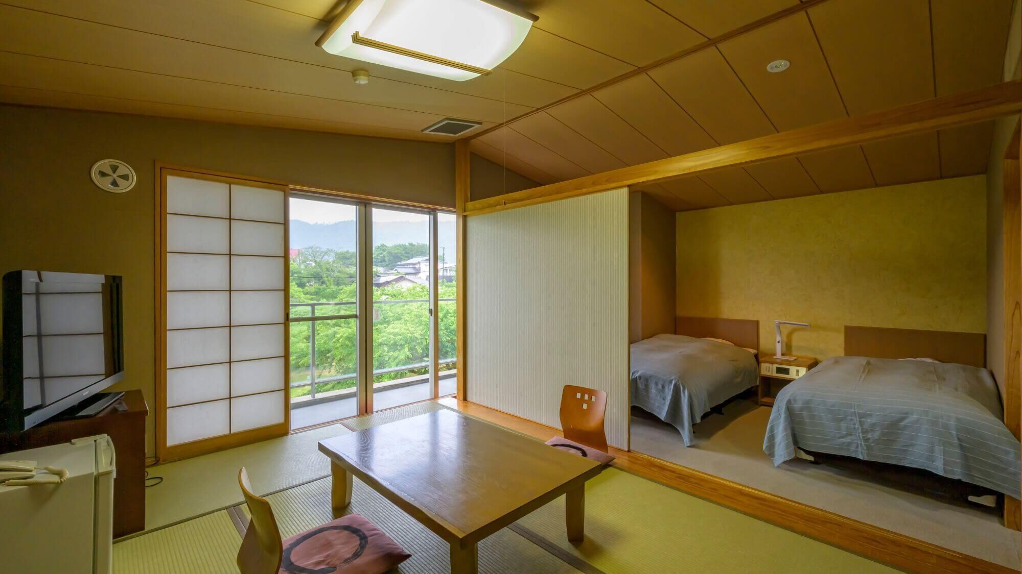 Una habitación tradicional japonesa con suelo de tatami, una puerta corredera shoji, una mesa de madera, dos camas, un televisor y vistas a zonas verdes.