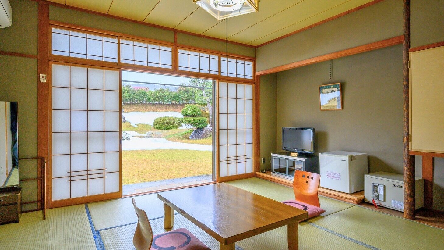 Una habitación japonesa tradicional con suelo de tatami, una mesa baja, un televisor y un refrigerador.