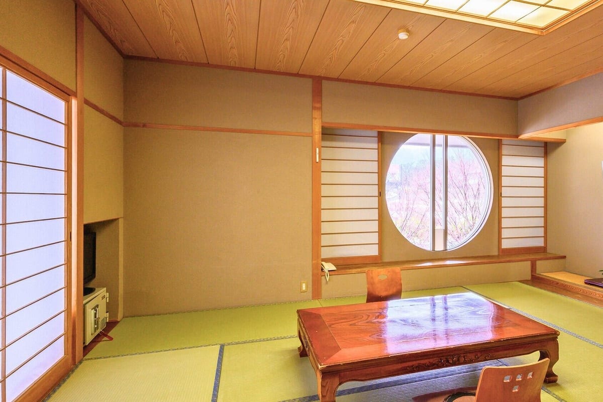 A traditional Japanese room with tatami flooring, a wooden table, and shoji screens.