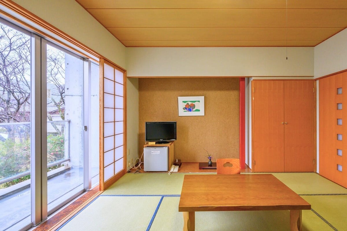 A traditional Japanese room with tatami flooring, a television, a small cabinet, and sliding doors.