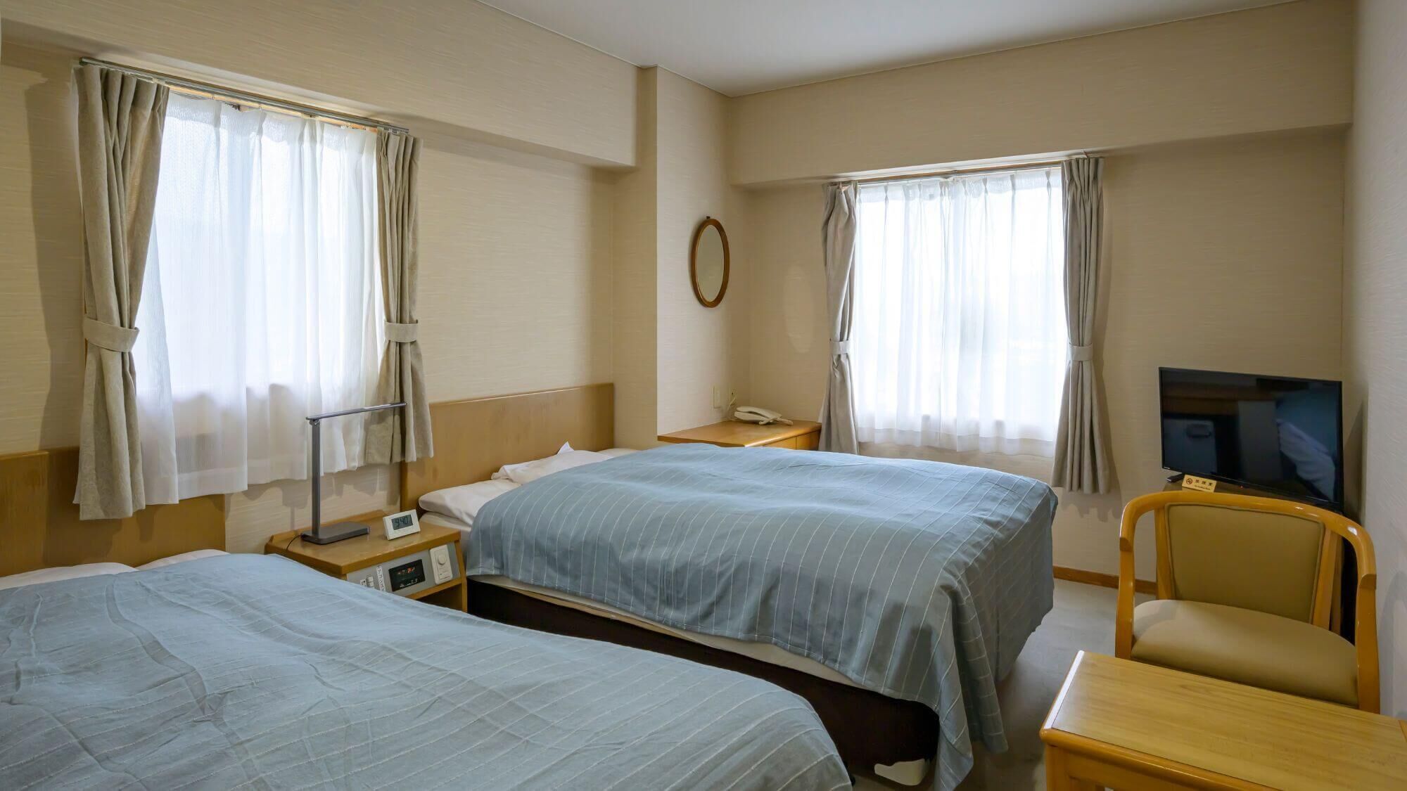Habitación de hotel con dos camas, televisor, escritorio y una silla.