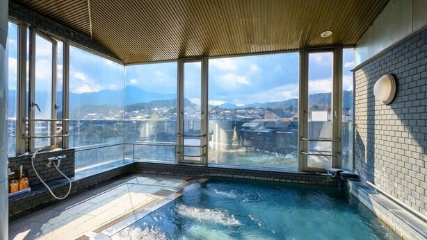 Uma banheira de hidromassagem com vista para um horizonte urbano através de grandes janelas.