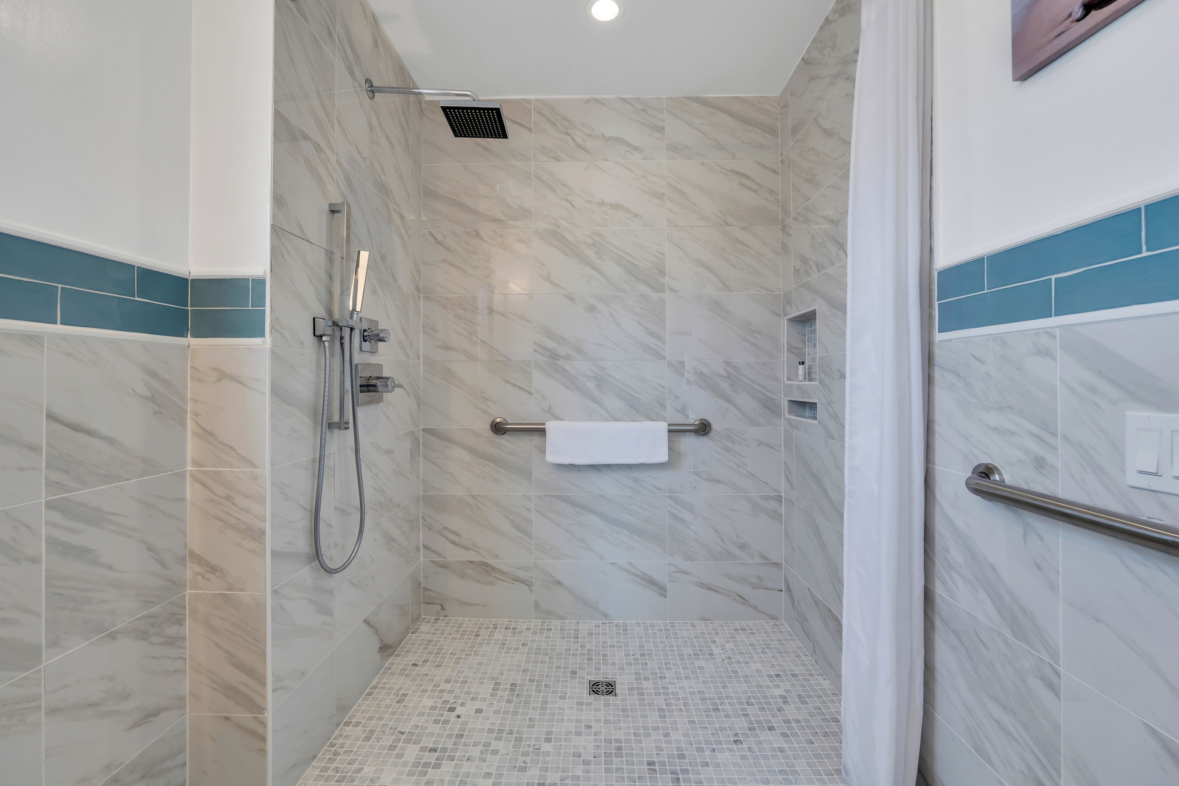 A modern bathroom with a shower, tiled walls, and a small shelf.