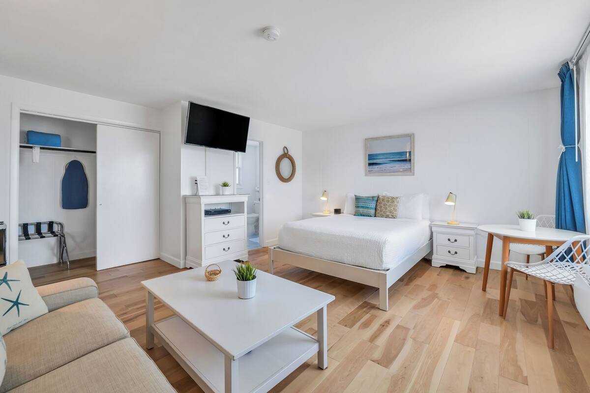 A modern, well-lit bedroom with a bed, bedside table, and a TV mounted on the wall.