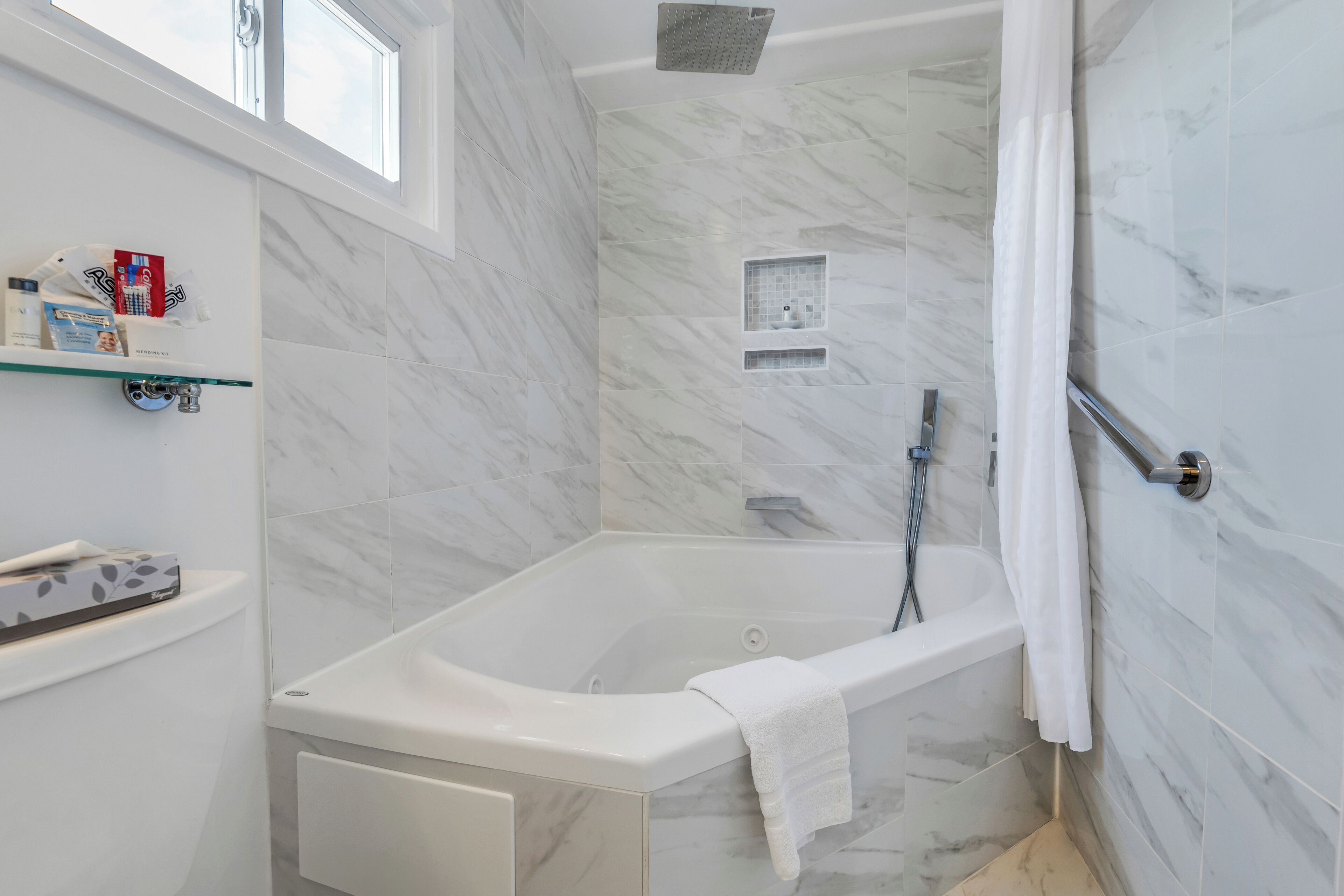 Un baño moderno con bañera, ducha y paredes de mármol.