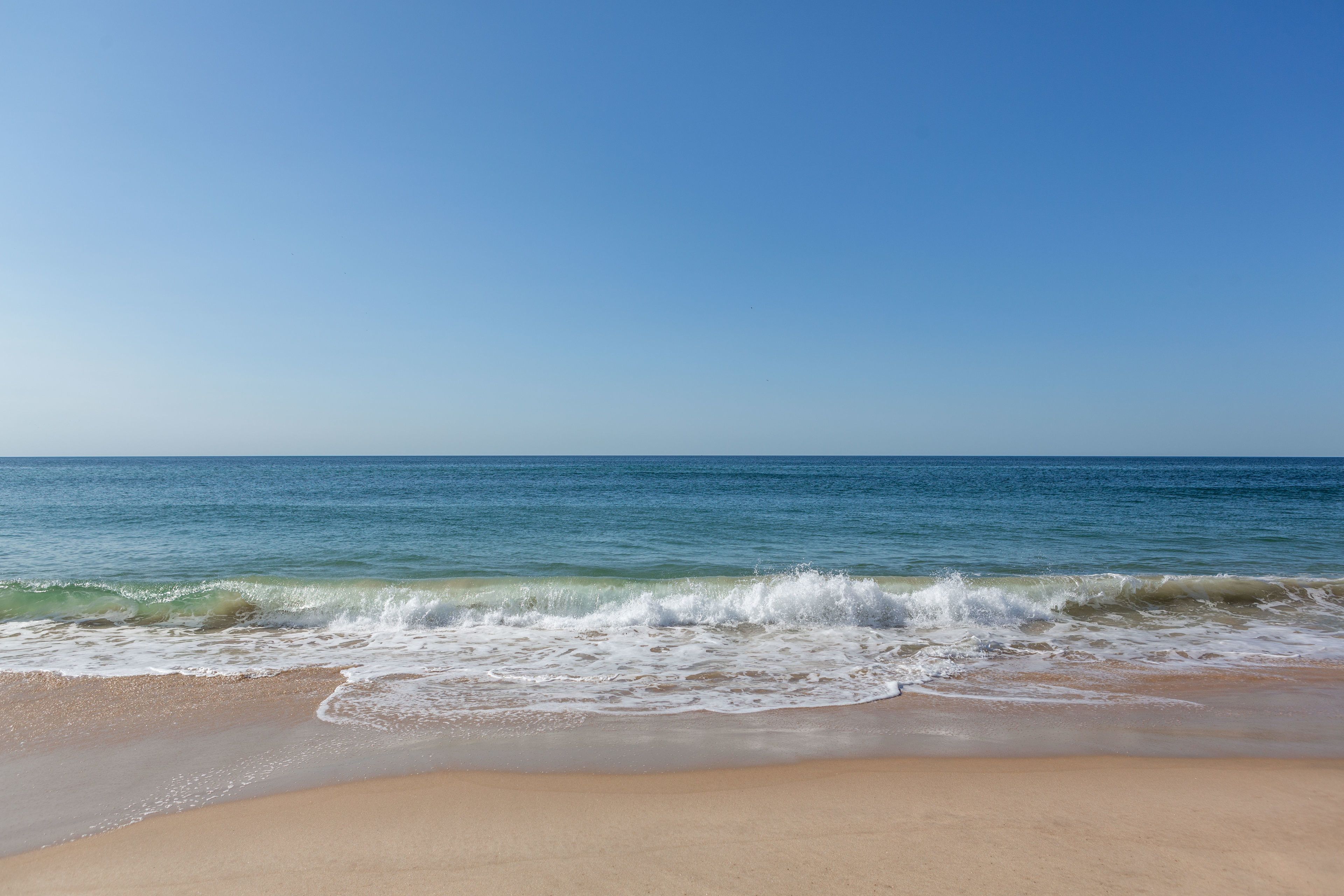 A beach with clear blue water and a sandy shore.