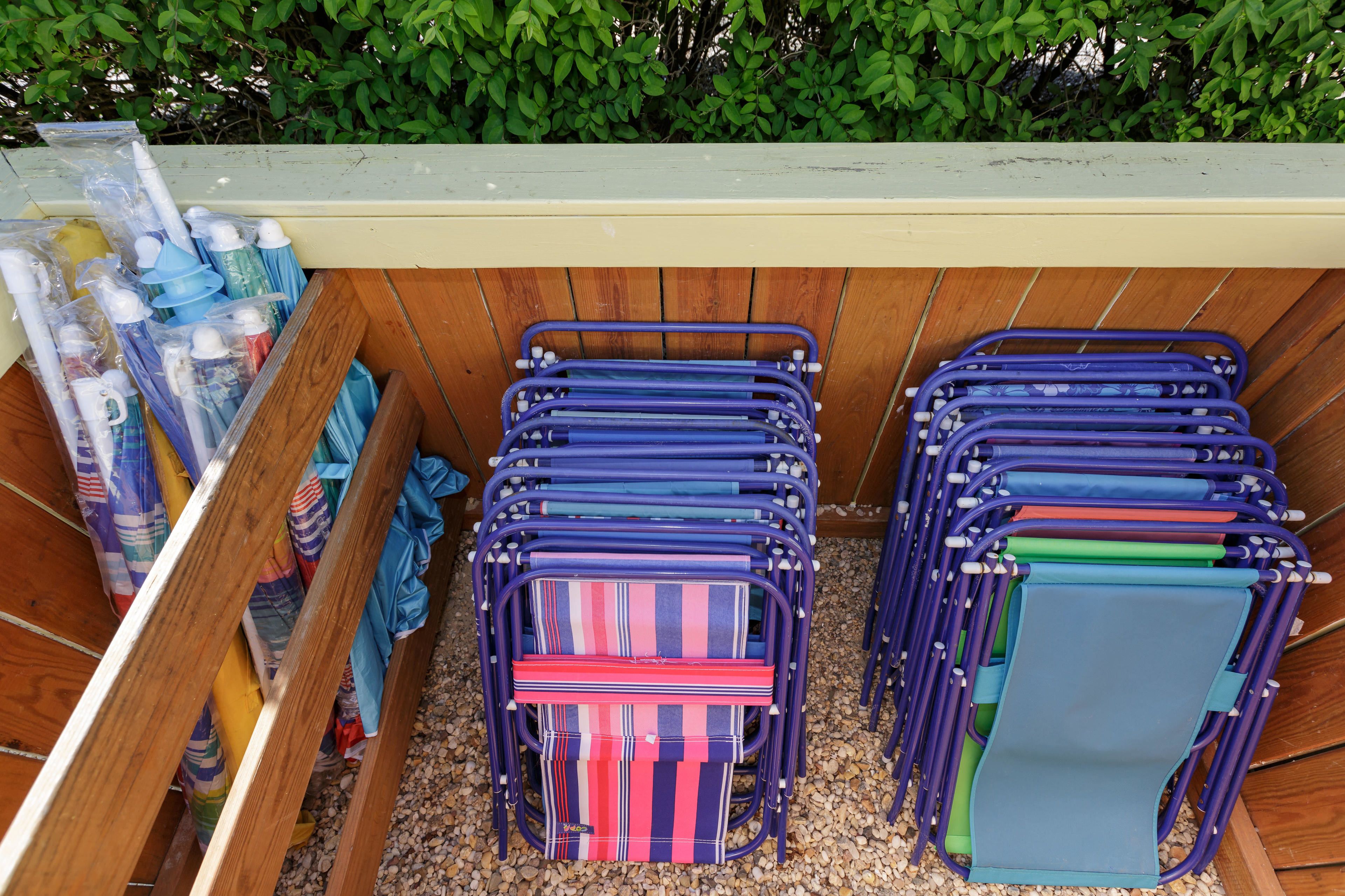 A storage area with neatly stacked folding chairs and umbrellas.