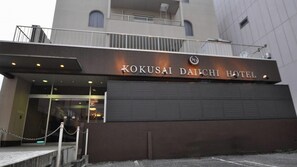 The exterior of the Kokusai Daiichi Hotel with a prominent entrance and a chain barrier. - Kokusai Daiichi Hotel (Oyama)