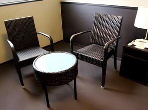 A corner room with two wicker chairs, a small round table, and a telephone on a nightstand. - Kokusai Daiichi Hotel (Oyama)