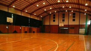 An indoor basketball court with a wooden floor, basketball hoops, and a high ceiling with exposed beams. - Hotel Famitic Myojin (Nikko)