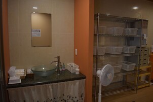 Un baño con lavamanos de cristal, un espejo y una repisa con cestas.
