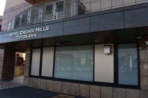Exterior do Hotel Crown Hills em Toyokawa, com fachada moderna, janelas amplas e varanda de metal.