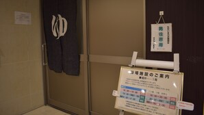 A bathroom with a towel hanging on the wall and a sign detailing the facility's operating hours. - Hotel Crown Hills Toyokawa (Toyokawa)
